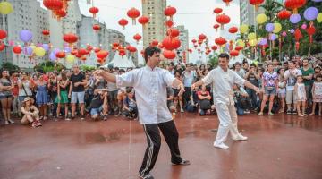 duas pessoas praticam tai chi em área decorada por balões. #paratodosverem