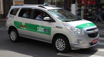 Táxi circulando em rua com passageiro. #paratodosverem