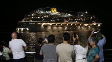 pessoas fotografam navio saindo à noite #paratodosverem 