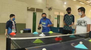 Professora joga tênis de mesa e alunos observam #paratodosverem