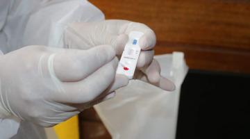 Teste rápido para detecção de covid. Mãos segura pequeno bastão onde é depositada uma cota de sangue. #Paratodosverem