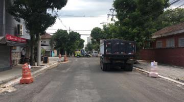 rua recém-asfaltada com cones e um caminhão parado do lado direito. #paratodosverem 