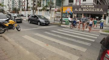 Pedestres atravessam em faixa na orla do Gonzaga em frente a veículos parados. #pratodosverem