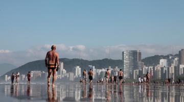 pessoas caminhando na beira da água na praia. #paratodosverem