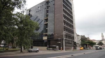 vista distante da fachada do prédio onde dicara a universidade, com grande avenida passando na frente. #paratodosverem