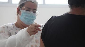 Enfermeira aplica vacina em braço de homem. #paratodosverem