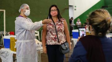 Enfermeiro mostra vacina para mulher e outra tira foto #paratodosverem