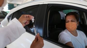 profissional segura frasco e mostra seringa com agulha para mulher dentro de carro. #paratodosverem