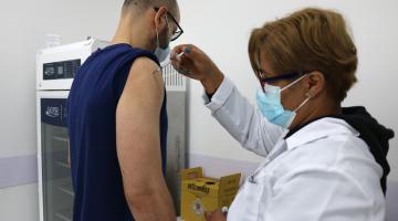 mulher vacina homem que está com a manga da camiseta suspensa. #paratodosverem