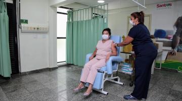 Mulher está sentada sendo vacinada. #Paratodosverem