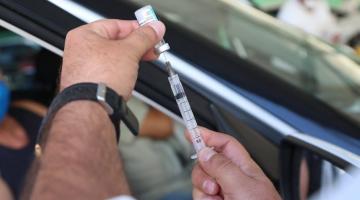 Uma mão está preparando uma injeção da vacina #paratodosverem