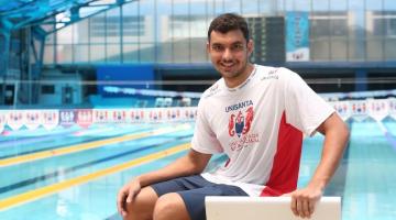 Nadador sentado em frente a piscina #paratodosverem