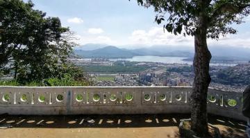 Vista da cidade a partir do alto da Vila Progresso. Em primeiro plano, uma árvore à direita e uma mureta com o formato tradicional de Santos. #paratodosverem