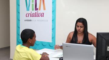 Jovem é atendido por mulher em VIla Criativa da Vila Progresso. #pracegover