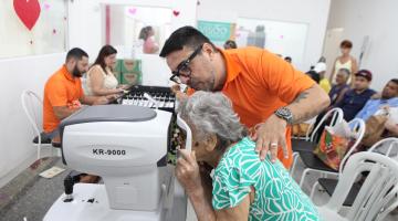 mulher coloca rosto em máquina de exame de vista. #paratodosverem