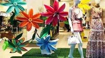 vitrine com flores na frente e manequins de roupas femininas. #paratodosverem