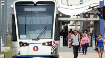 carro do vlt parado em estação. Passageiros na estação ao lado direito. #paratodosverem