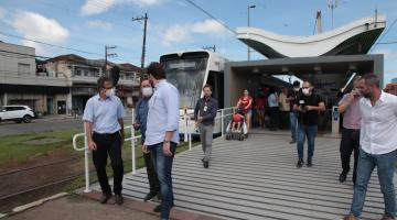 Vários homens em estação do VLT com modal parado à esquerda. #paratodosverem