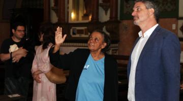 mulher uniformizada mostra ambiente de igreja para homem. #paratodosverem
