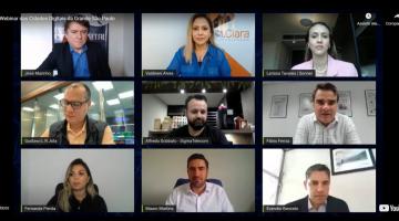 Nove participantes de webinar aparecem em tela de notebook. #paratodosverem