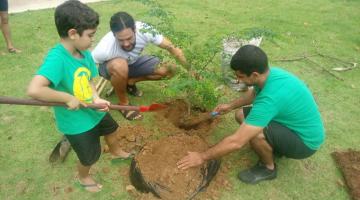 dois rapazes e criança plantam árvore #pracegover 