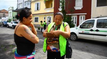 agente aborda mulher na rua com prancheta #pracegover 