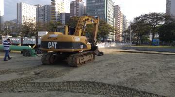 Escavadeira está na praia junto ao canal. #Pracegover