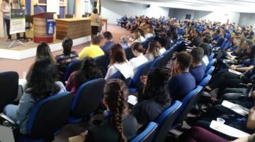 pessoas sentadas no auditório durante o evento #pracegover 