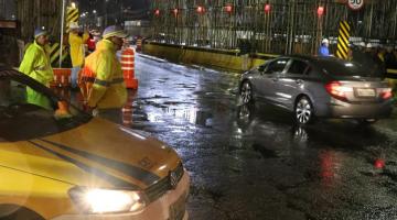 À noite, com a pista molhada de chuva, carro passa sob estrutura metálica da Avenida Martins Fontes observados por dois agentes uniformizados da CET
