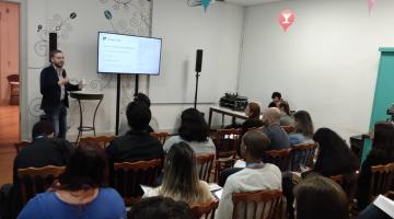 pessoas sentadas em sala vendo a apresentação da ferramenta #pracegover 