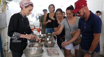 Mulher de uniforme preto serve ceviche a fila de pessoa