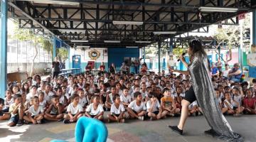 Artistas fazem apresentação para crianças em grande galpão. #Pracegover