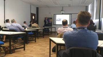 pessoas em sala de aula olham para telão #pracegover 