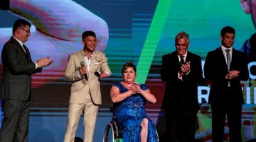 Atleta recebendo o prêmio no palco #pracegover 