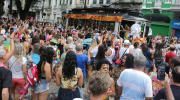 #pracegover Cerca de 300 pessoas observam bonde decoração de carnaval chegando à praça