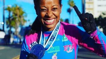 A paratleta Vanessa Cristina de Souza segura medalha no peito e sorri para foto. #Paratodosverem