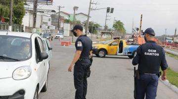 #pracegover em avenida, Dois guardas municipais abordam motorista dentro de carro, com veículo da C.E.T. ao fundo 