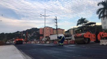 Trecho de pista recém-pavimentada, com máquina compactadora. #Paratodosverem