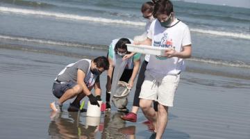 pessoas colhem e observam lixo encontrado no mar #paratodosverem