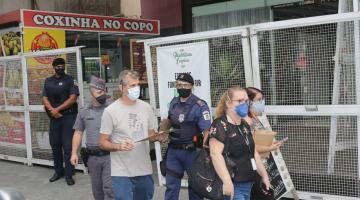 fiscais e guardas andam de máscara na calçada, um deles com prancheta #paratodosverem