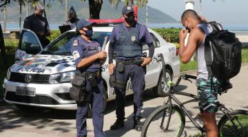 Guardas municipais ao lado de viatura orientam ciclista a colocar máscara. #Paratodosvem