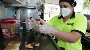 Mulher está preparando lanche em chapa. #Paratodosverem