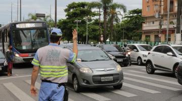 agente de trânsito orientando carros e ônibus em avenida #paratodosverem