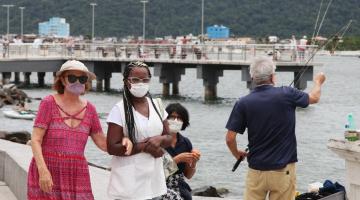 pessoas andam na orla de máscaras #paratodosverem 