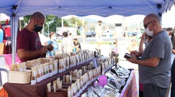 homem abre carteira para pagar por produto em barraca da feira #paratodosverem