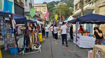 rua decorada com bandeirinhas e barracas nas laterais. #paratodosverem