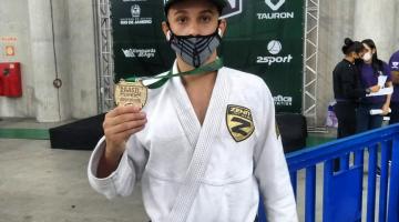 Atleta exibe medalha e cinturão conquistados na competição. #paratodosverem