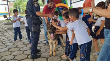 Crianças passam a mão em cachorro do canil da guarda com agente ao lado #paratodosverem