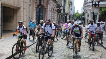 Pessoas andando de bicicleta em via do centro histórico de santos #paratodosverem