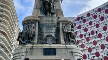 vice-prefeita e principe ao lado de coroa de flores na frente de monumento #paratodosverem